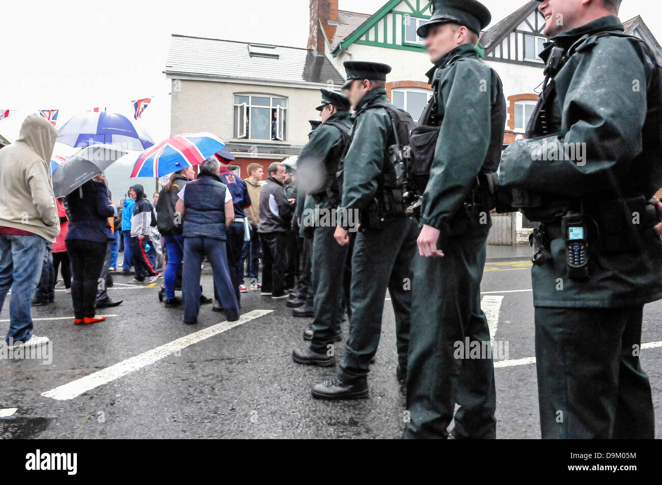 Uniformata PSNI gli ufficiali di polizia che indossa giacche ad alta visibilità formano una linea attraverso una strada per fermare una folla dal procedimento Foto Stock