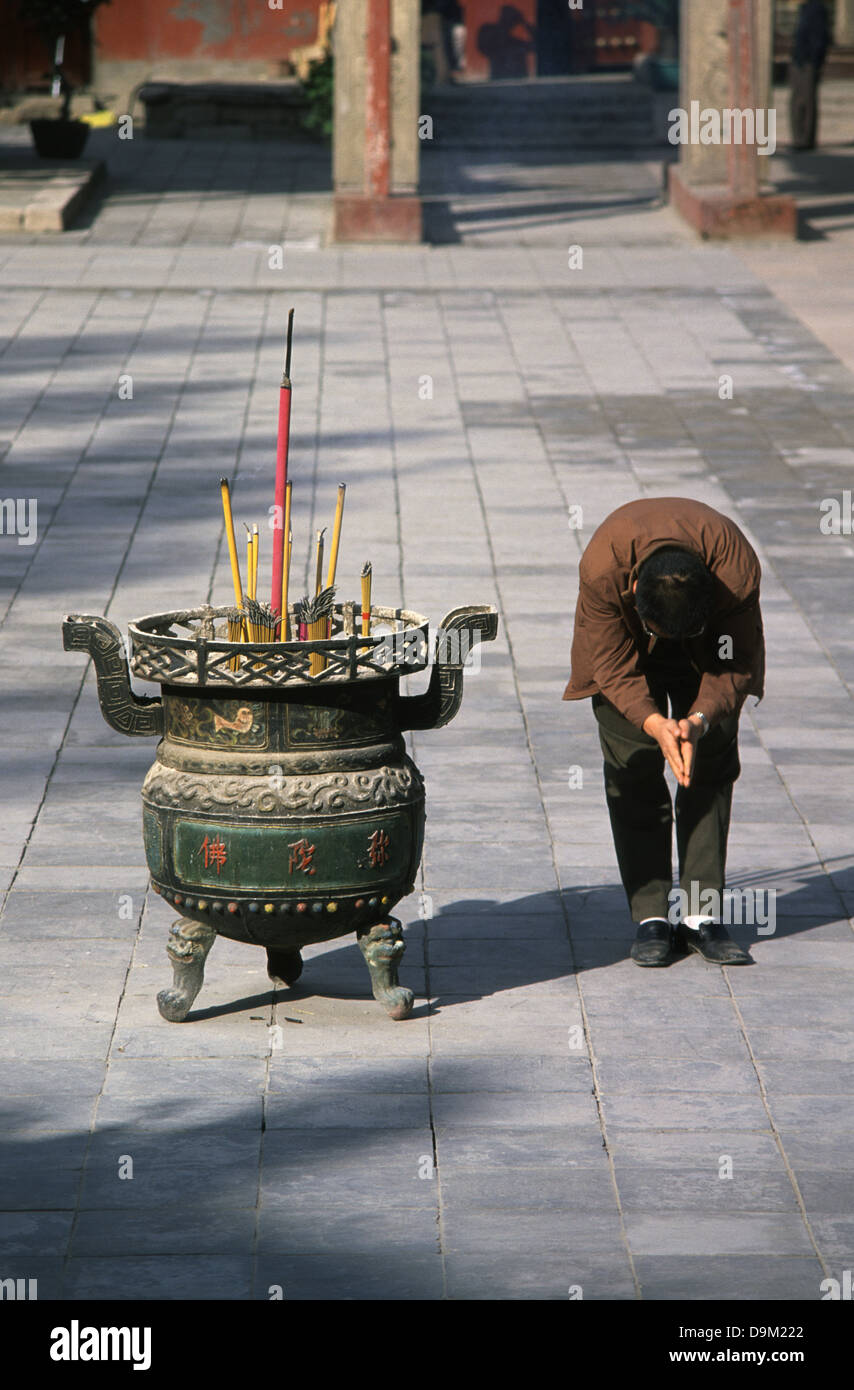 Un uomo cinese prosternerà all'interno dell'antico tempio buddista Dafo Si o Grande Tempio del Buddha di Zhangye in una prefettura-città di livello nel centro di provincia di Gansu in Cina Foto Stock