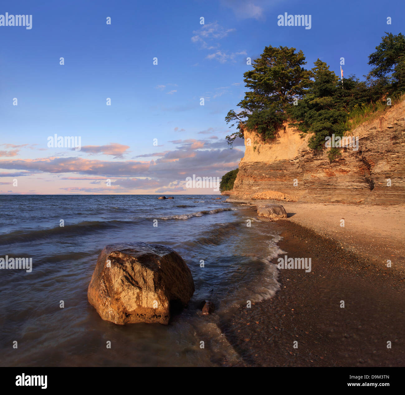 Un masso in seduta il surf con scogliere dietro a irradiare la luce del mattino, il Lago Erie a Barcellona Beach, New York, Stati Uniti d'America Foto Stock