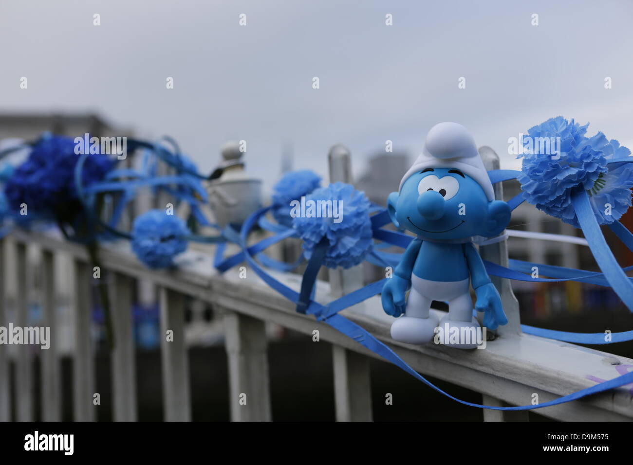 Dublino, Irlanda. Il 22 giugno 2013. L'Ha'penny Bridge è decorata con fiori blu e piccolo Puffo figurine per Global Puffi giorno. Attori vestiti come Papa Puffo e Smurfette poste a Dublino ha dell'penny Bridge in una promozione per la prossima "puffi 2' film. La foto chiamata era tenuto a livello globale i puffi Giornata, che si celebra in tutto il compleanno dei puffi' Payo creatore. Credito: Michael Debets/Alamy Live News Foto Stock