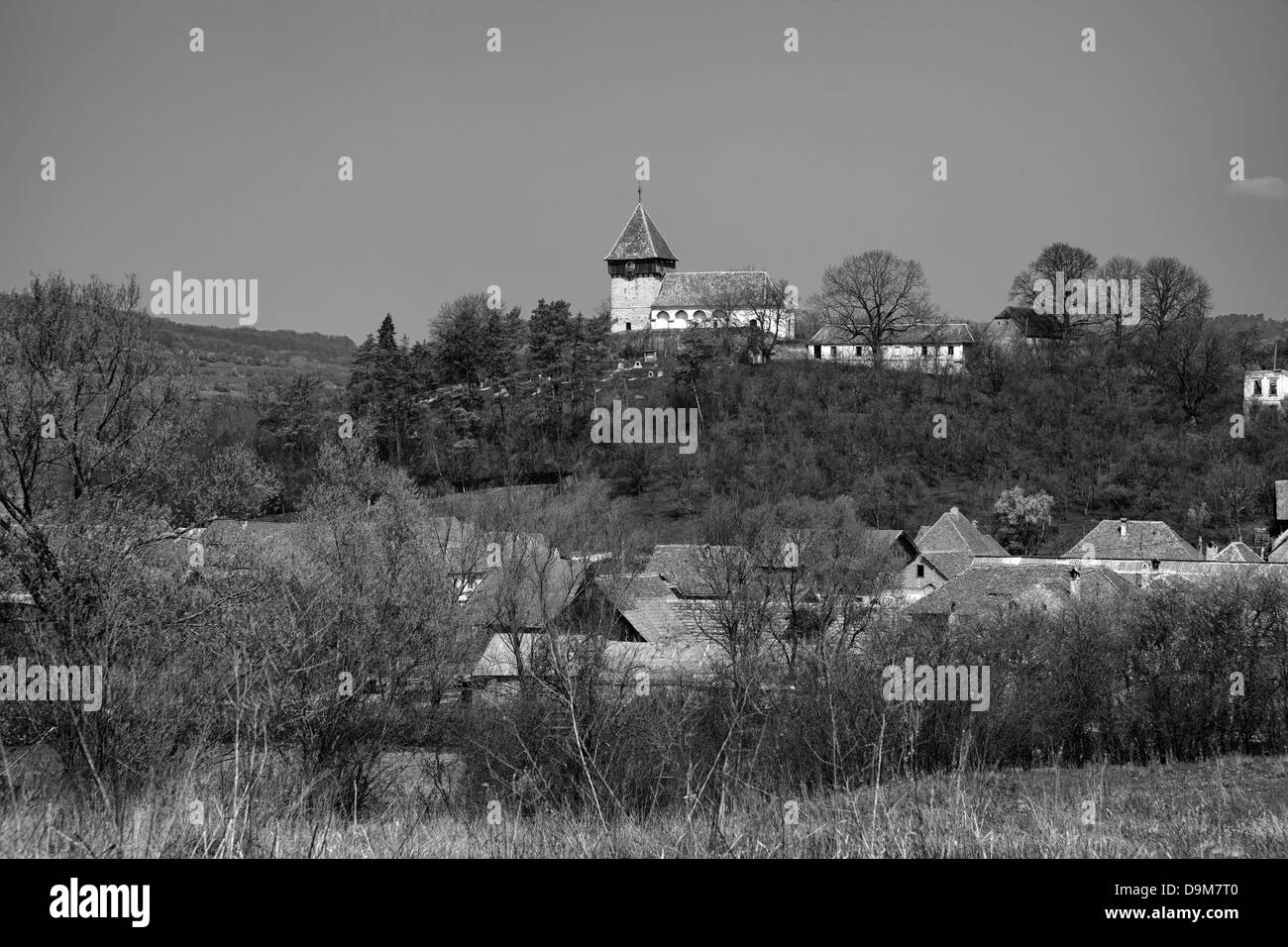 Visualizzazione bianco e nero del villaggio della Transilvania di Rodbav con la chiesa sulla collina, Romania. Foto Stock