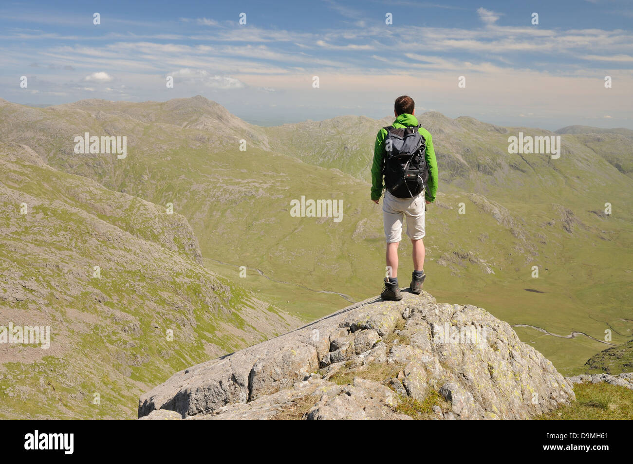 Walker su Scafell affacciato sulla grande Moss verso Bowfell e Crinkle Crags nel Lake District inglese Foto Stock