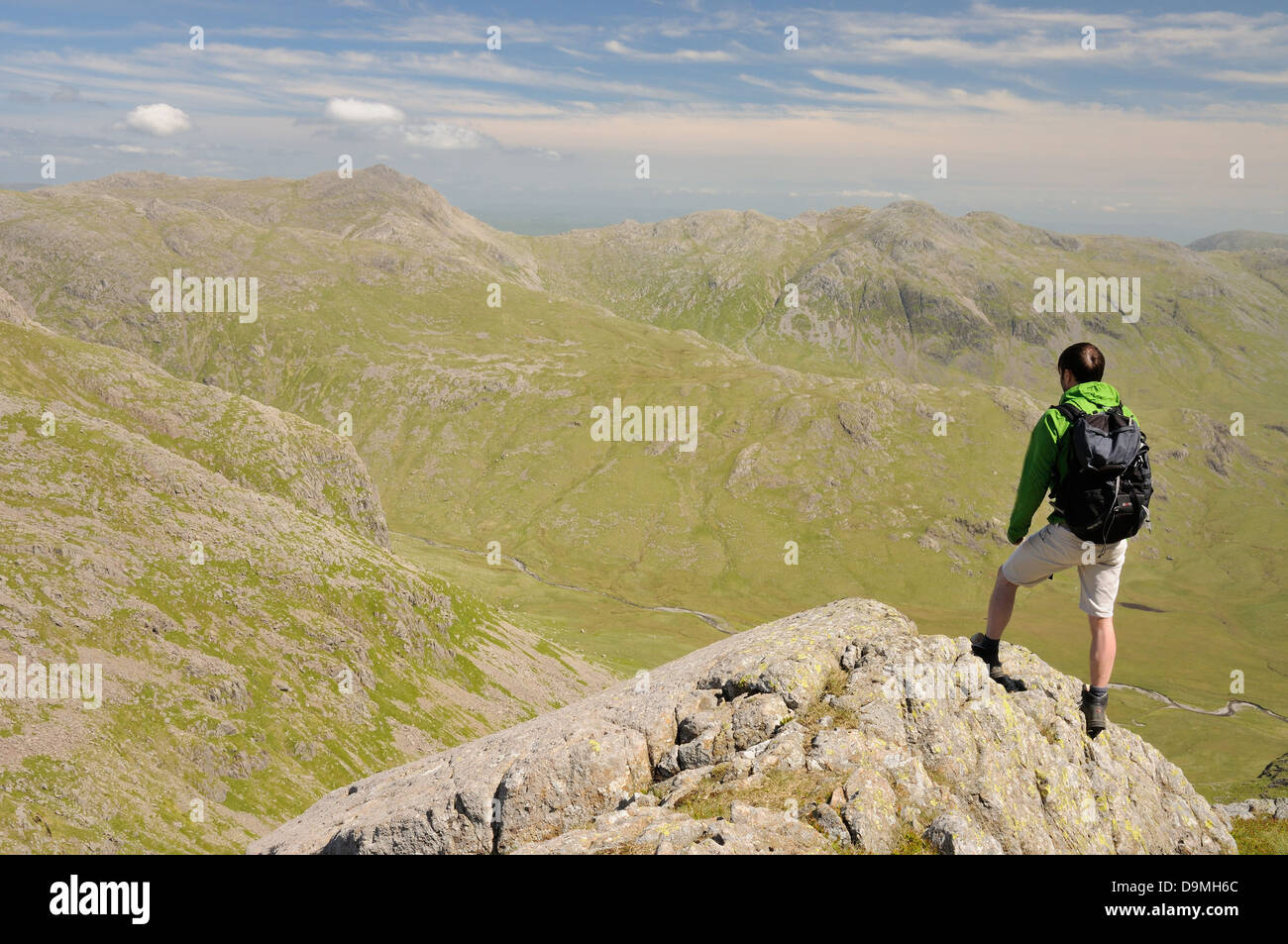 Walker su Scafell affacciato sulla grande Moss verso Bowfell e Crinkle Crags nel Lake District inglese Foto Stock