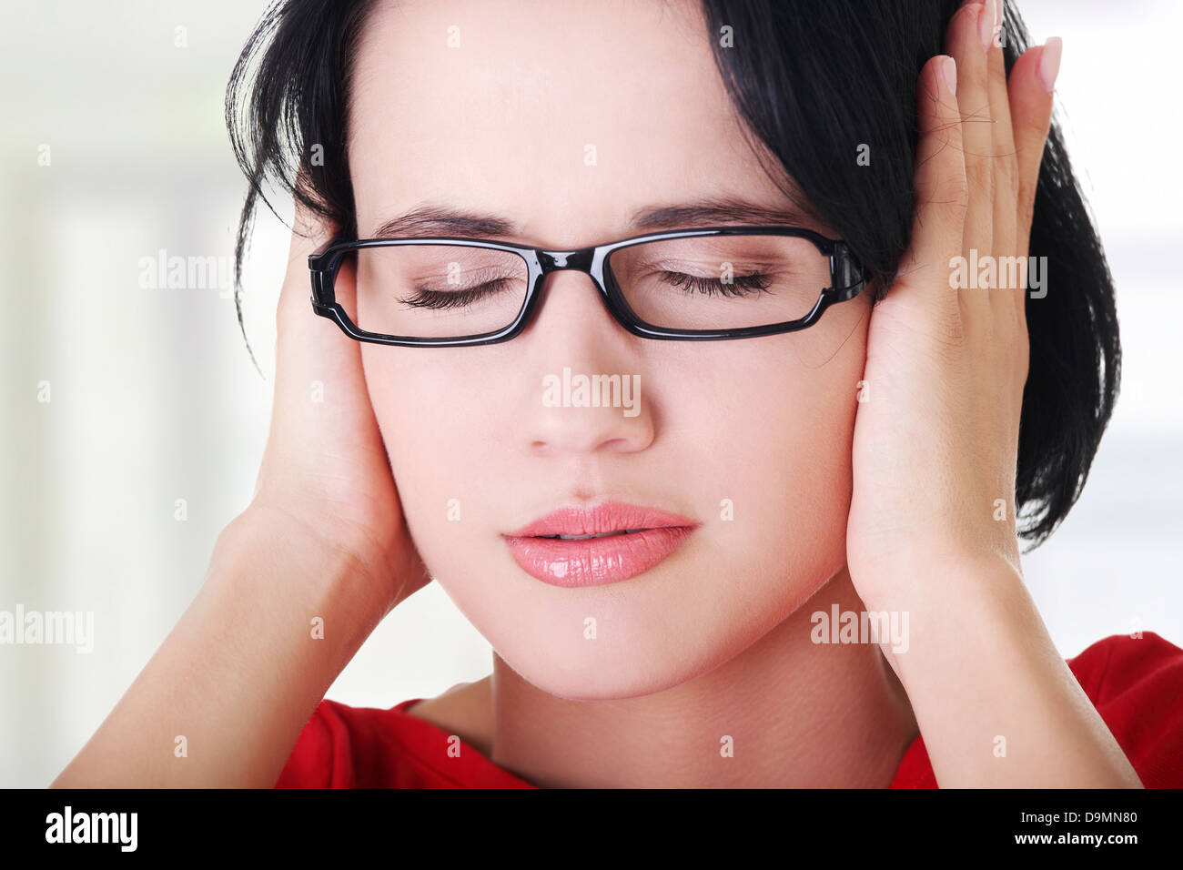 Primo piano della frustrato giovane donna tenendo le sue orecchie Foto Stock
