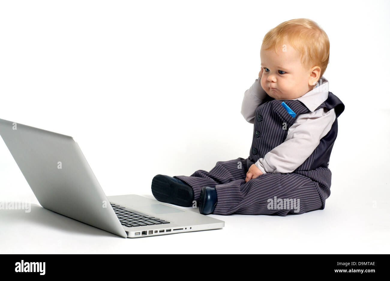 Blonde baby in tuta a lavorare con il computer portatile e il pensiero Foto Stock