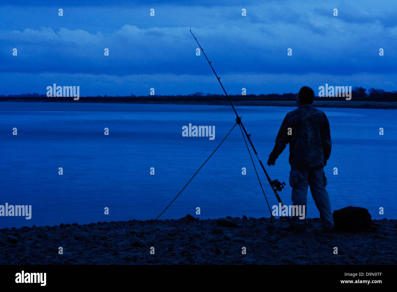 Silhouette del pescatore di colata sulla spiaggia all'alba di un metodo popolare per la pesca in mare per la cattura di acqua salata pesce Foto Stock
