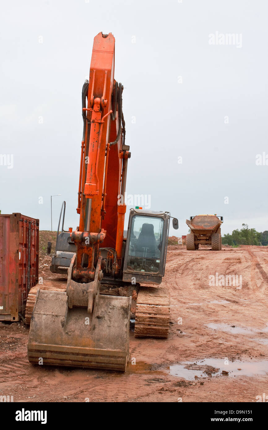 Massa Industriale Escavatore con camion in background in una strada sito in costruzione Foto Stock