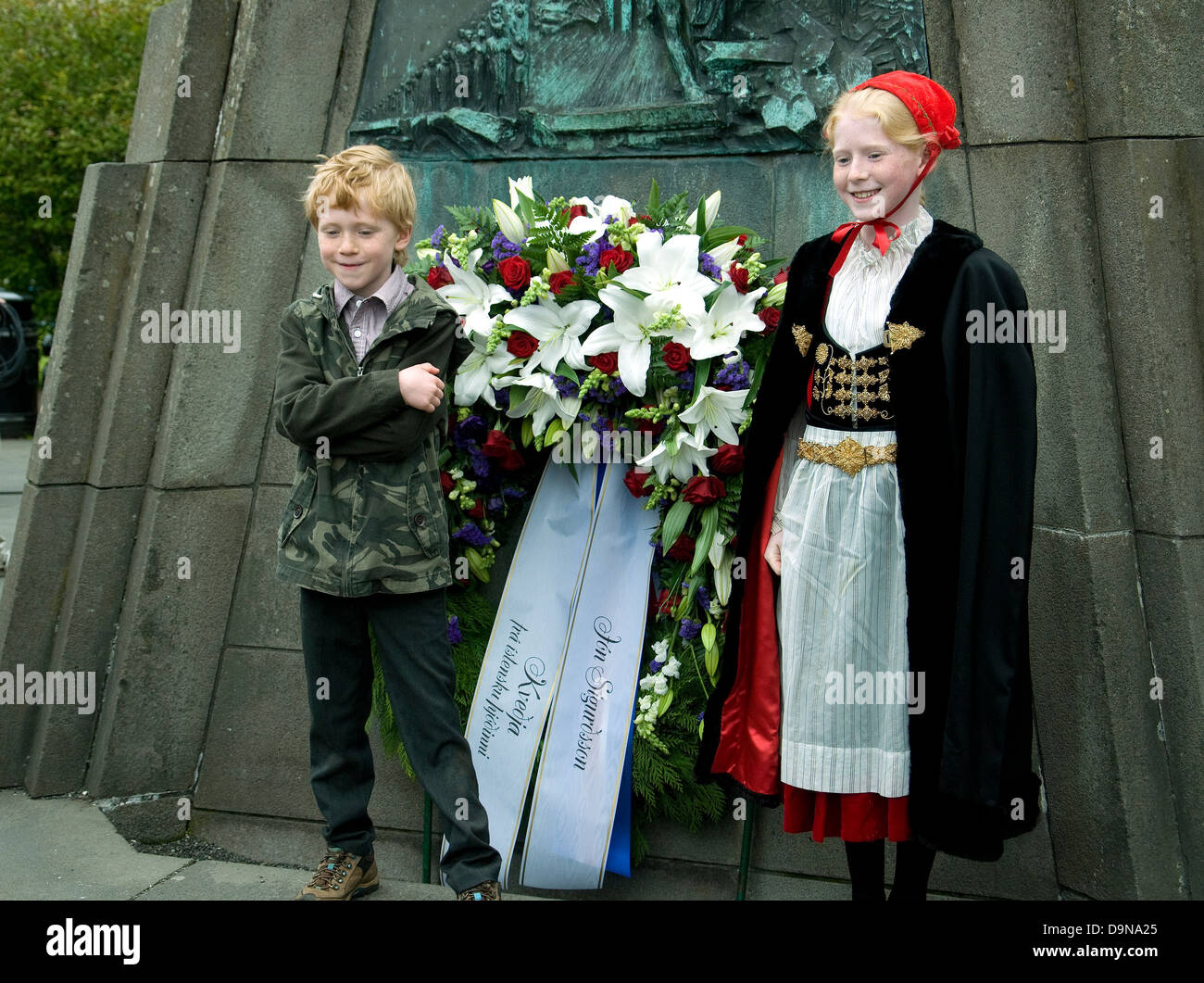 A Reykjavik, in Islanda anniversario di indipendenza, due ragazzi pongono a un memoriale--la ragazza in abito nazionale e cappuccio rosso Foto Stock