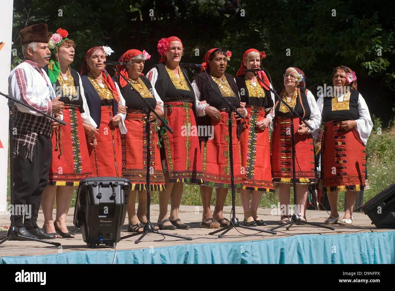 Uomini donne bambini vestiti nei tradizionali costumi nazionali singing competition intrattenere i visitatori e viaggiatori, Bulgaria Foto Stock