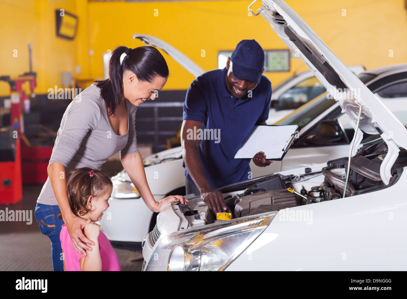 Felice madre e bambina in auto il centro di servizio con auto tecnico Foto Stock