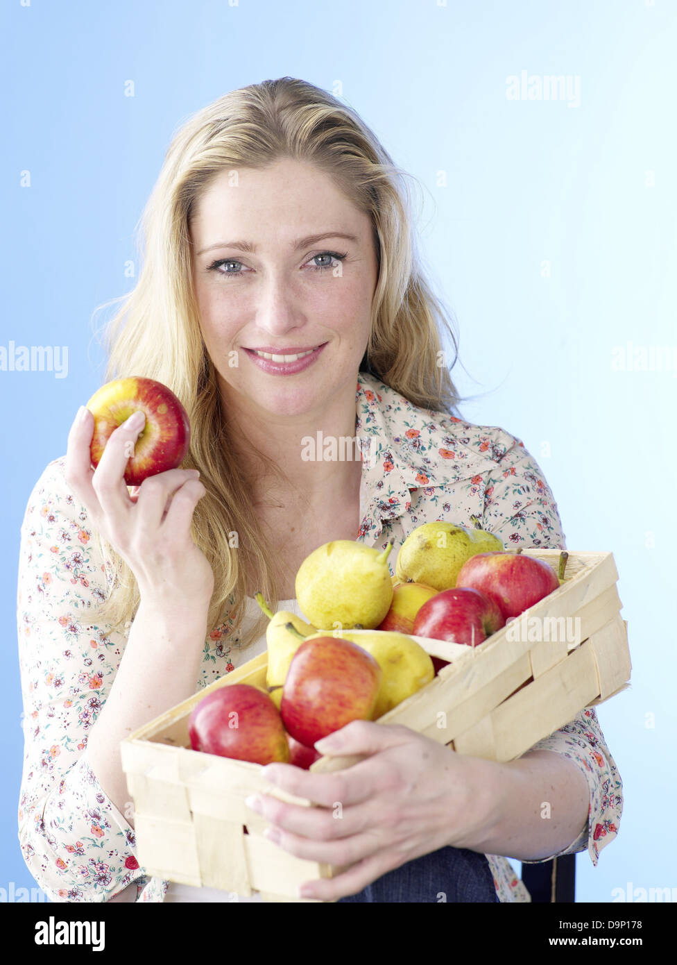 Donna bionda con un cesto di frutta Foto Stock