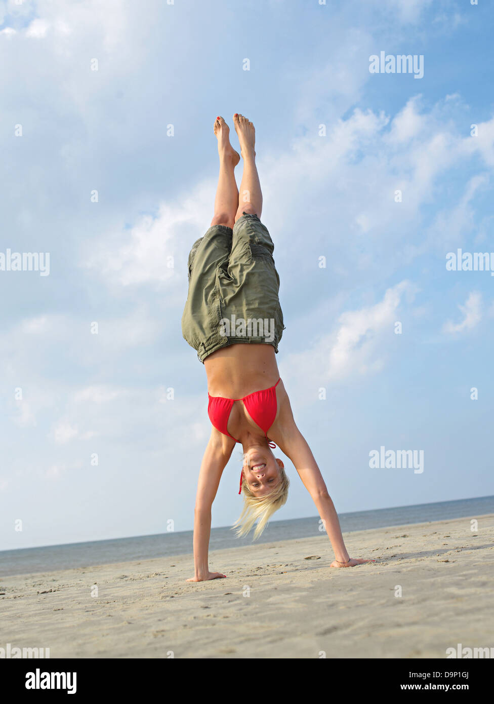Giovane donna fa un handstand sulla spiaggia Foto Stock