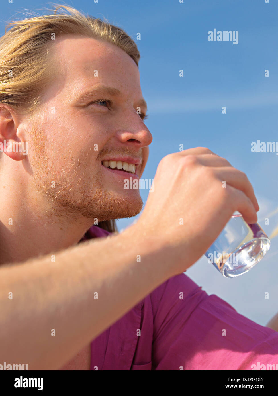 Giovane uomo sulla spiaggia dringing un bicchiere di acqua Foto Stock