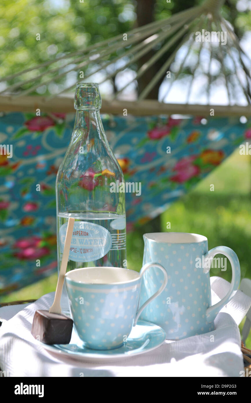 Bottiglia di acqua, cup, per lecca-lecca di cioccolato e amaca in giardino Foto Stock