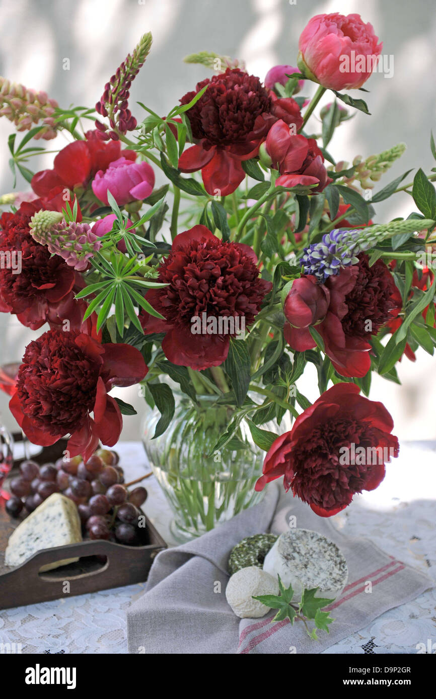 Mazzo di fiori rossi, formaggio e uve rosse Foto Stock