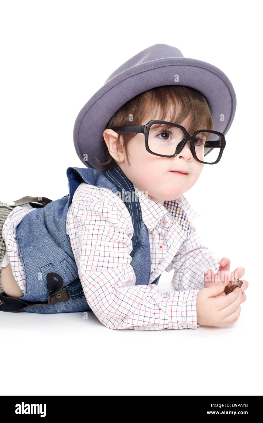 Carino smart baby kid con il cappello e occhiali mangiare il cioccolato Foto Stock