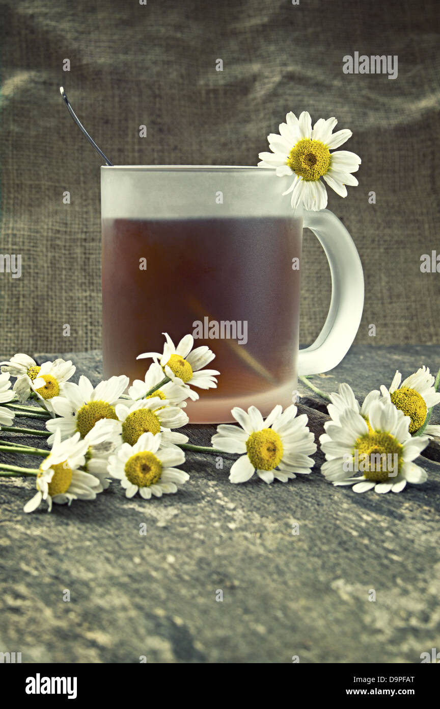 Tazza di tè e camomilla fiori su un tavolo di legno. Profondità di campo. Foto Stock