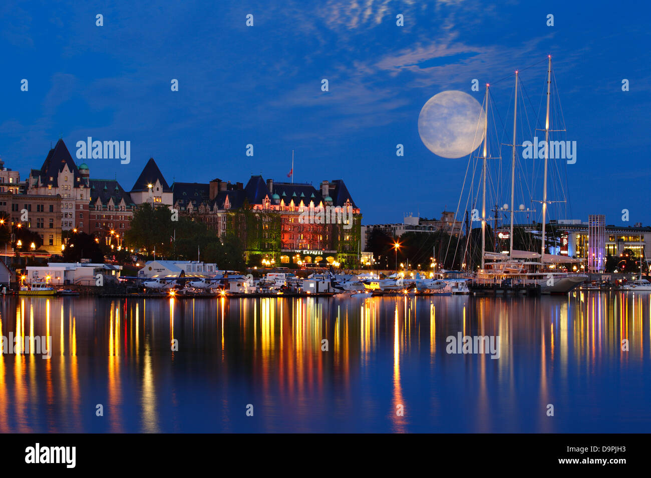 La luna piena sorge dietro il Empress Hotel e yacht di lusso Athena al crepuscolo-Victoria, British Columbia, Canada. Composito Digitale. Foto Stock