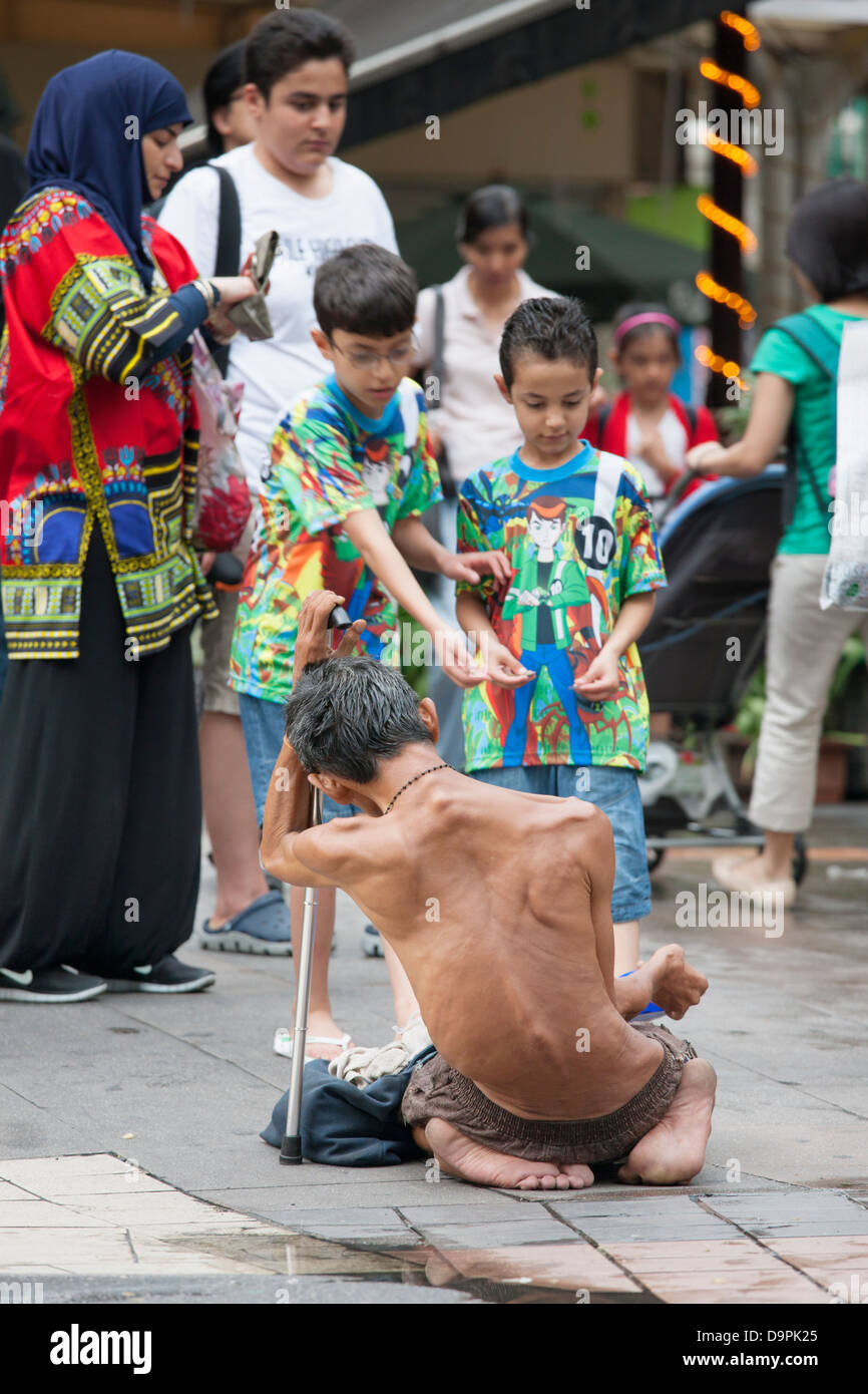 I bambini dando mendicante denaro, Bukit Bintang, Kuala Lumpur, Malesia Foto Stock