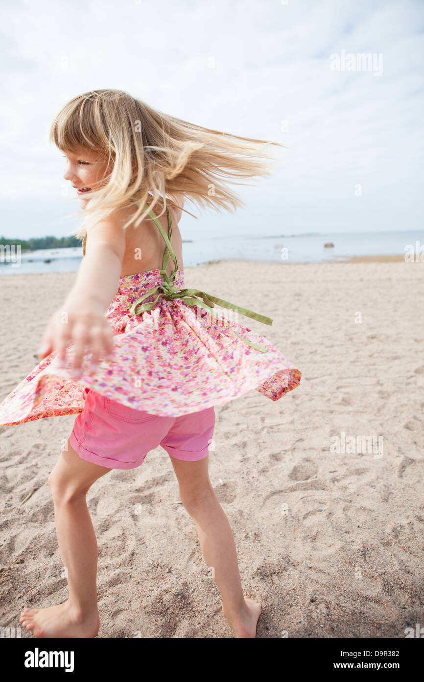 Sorridente giovane ragazza a piedi nudi con rosa abito modellato e pantaloni  per divertirsi in spiaggia con vista oceano in background Foto stock - Alamy