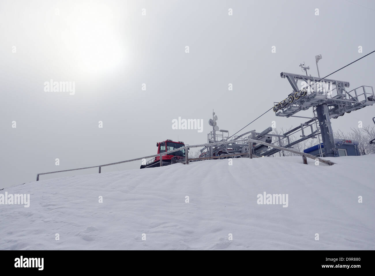 Il gatto delle nevi in appoggio sulla sommità di una pista da sci Foto Stock