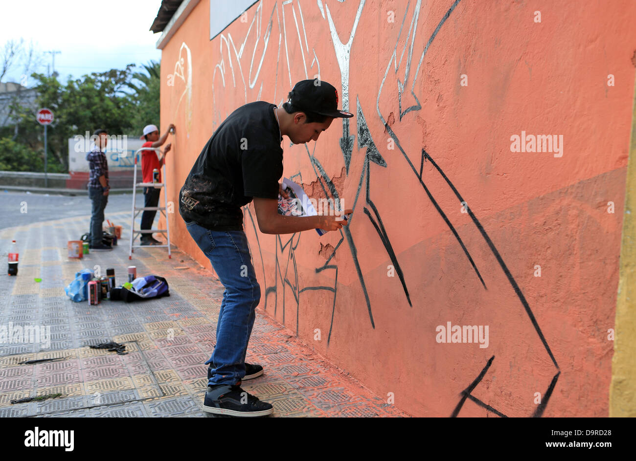 Teenager artisti di strada creare graffiti con autorità locali il permesso per le strade di Otavalo, Ecuador Foto Stock