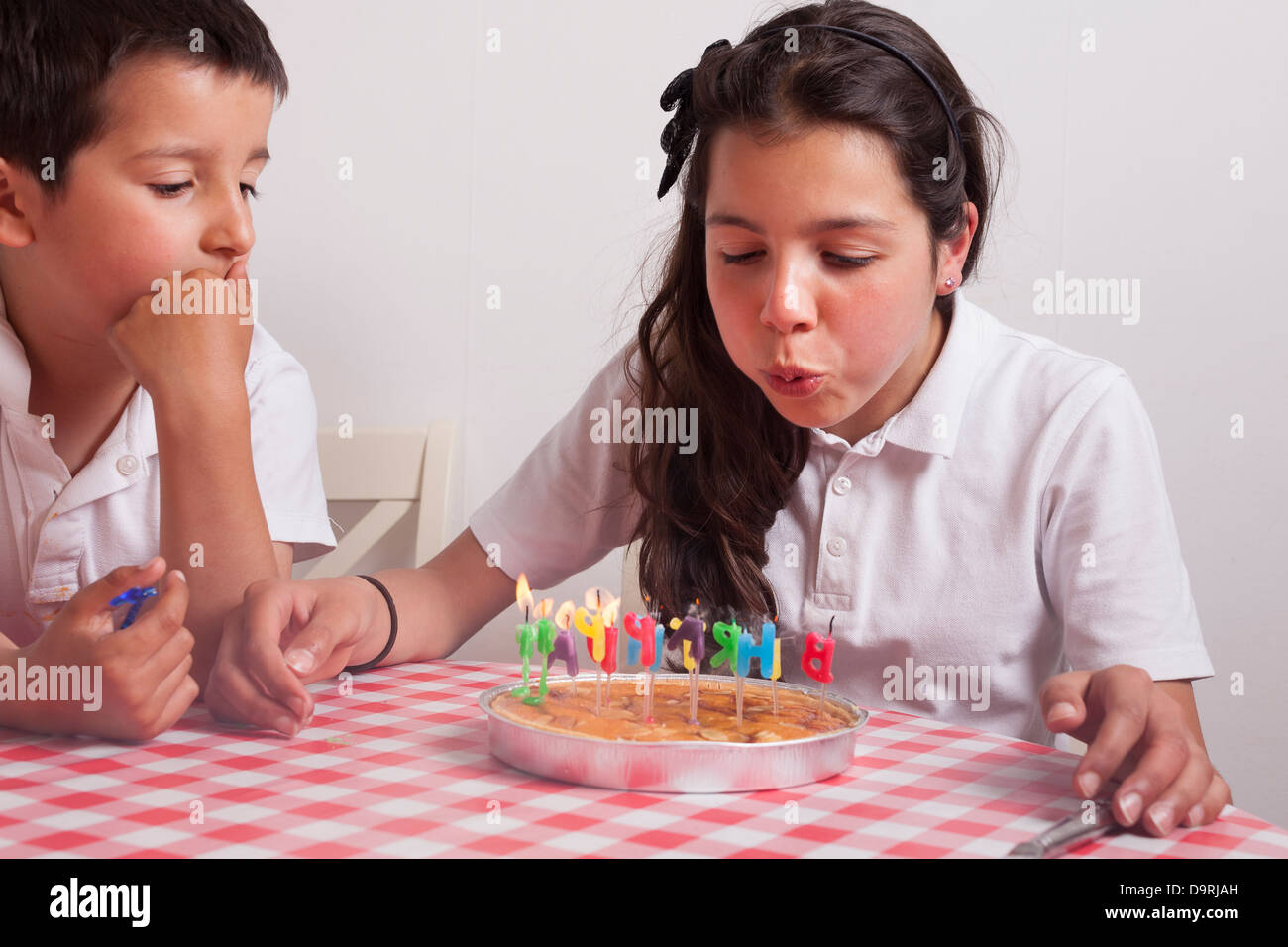 Giovane ragazza soffia-out candele su una torta di compleanno Foto Stock