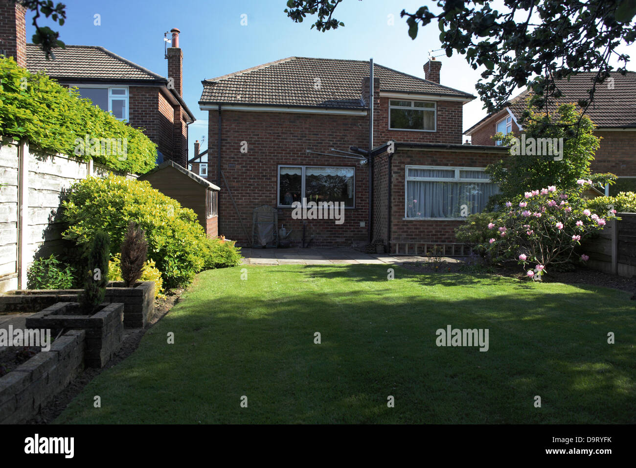 British UK House costruita nel giardino recintato degli anni Cinquanta In prima estate con prato e letti di fiori curati Foto Stock