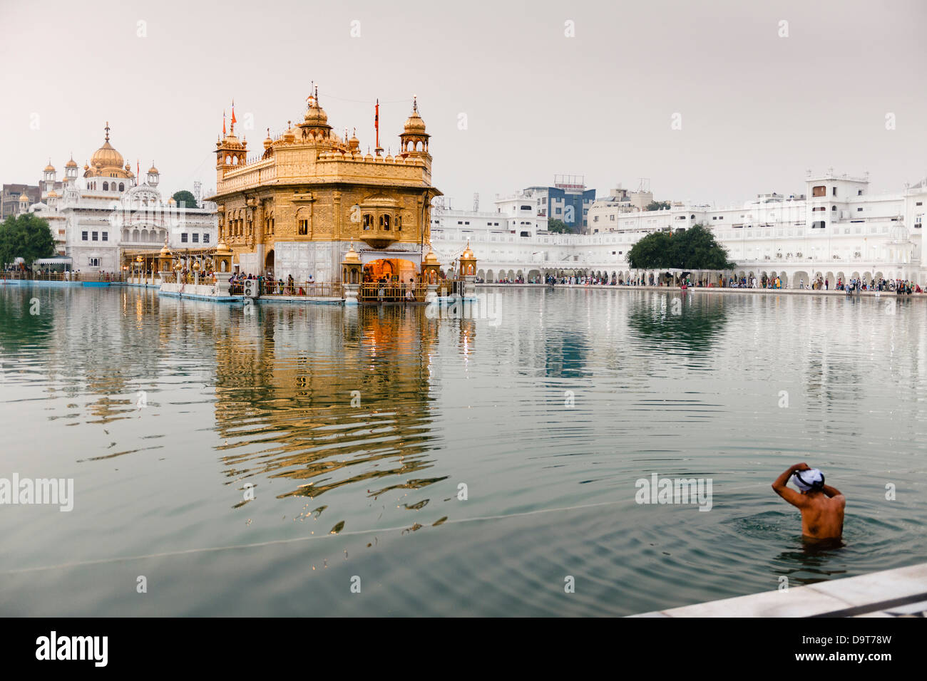 Il bagno nella piscina del nettare di immortalità presso il Tempio d'oro di Amritsar, India. Foto Stock