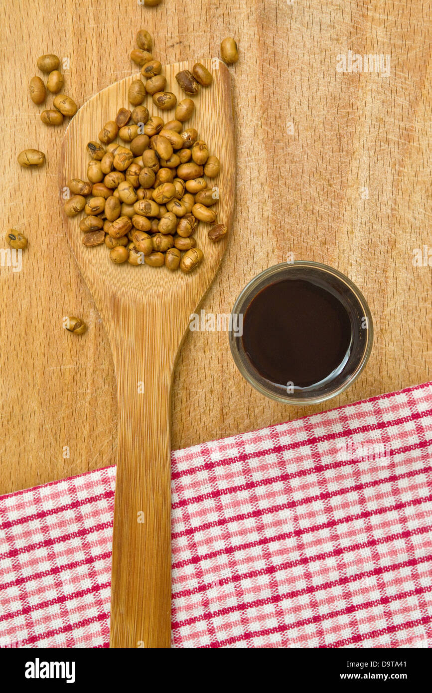 La salsa di soia con semi di soia su legno arnese da cucina sul tavolo. Foto Stock