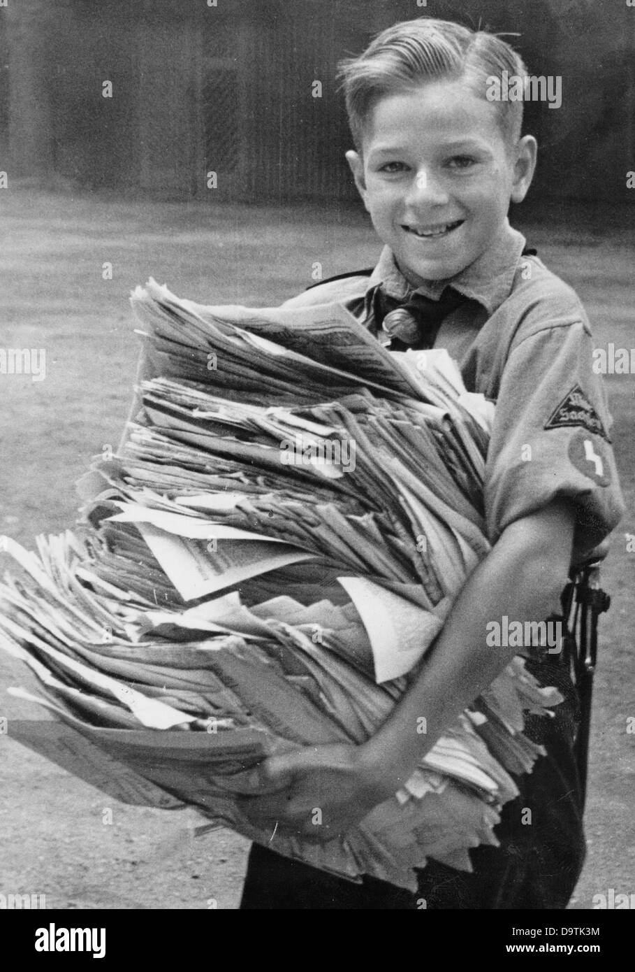 Un ragazzo, che indossa l'uniforme della Gioventù tedesca, ha raccolto vecchi giornali e li sta portando al punto di raccolta della carta dei rifiuti, nell'agosto 1942. Fotoarchiv für Zeitgeschichte Foto Stock