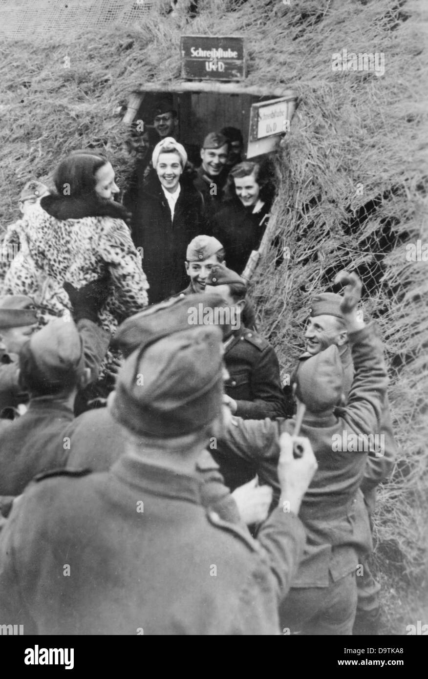 I soldati sono raffigurati con attrici di un gruppo teatrale sul Fronte Orientale, pubblicato il 29 febbraio 1944. La Propaganda nazista! Sul retro dell'immagine si legge: 'spettacolo di varietà nel bunker. L arrivo di attrici di una parte anteriore del gruppo di teatro che il 'Spiess' (Lancia - soprannome per la società Sergente Maggiore) ha annunciato. Pieno di previsione, i soldati folla insieme davanti alla batteria di bunker a trasportare il ballerino e cantante sulle loro spalle verso il bunker. Con humoros gridando, gli uomini di dimostrare la loro gioia per la piacevole interruzione del dovere quotidiano." Foto: Berliner Verlag/Ar Foto Stock