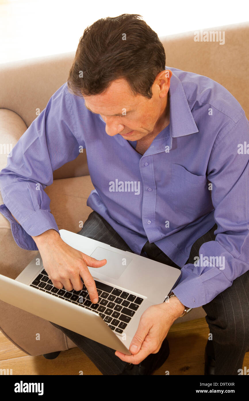 Guardando verso il basso su un uomo seduto su un divano con un notebook. Foto Stock