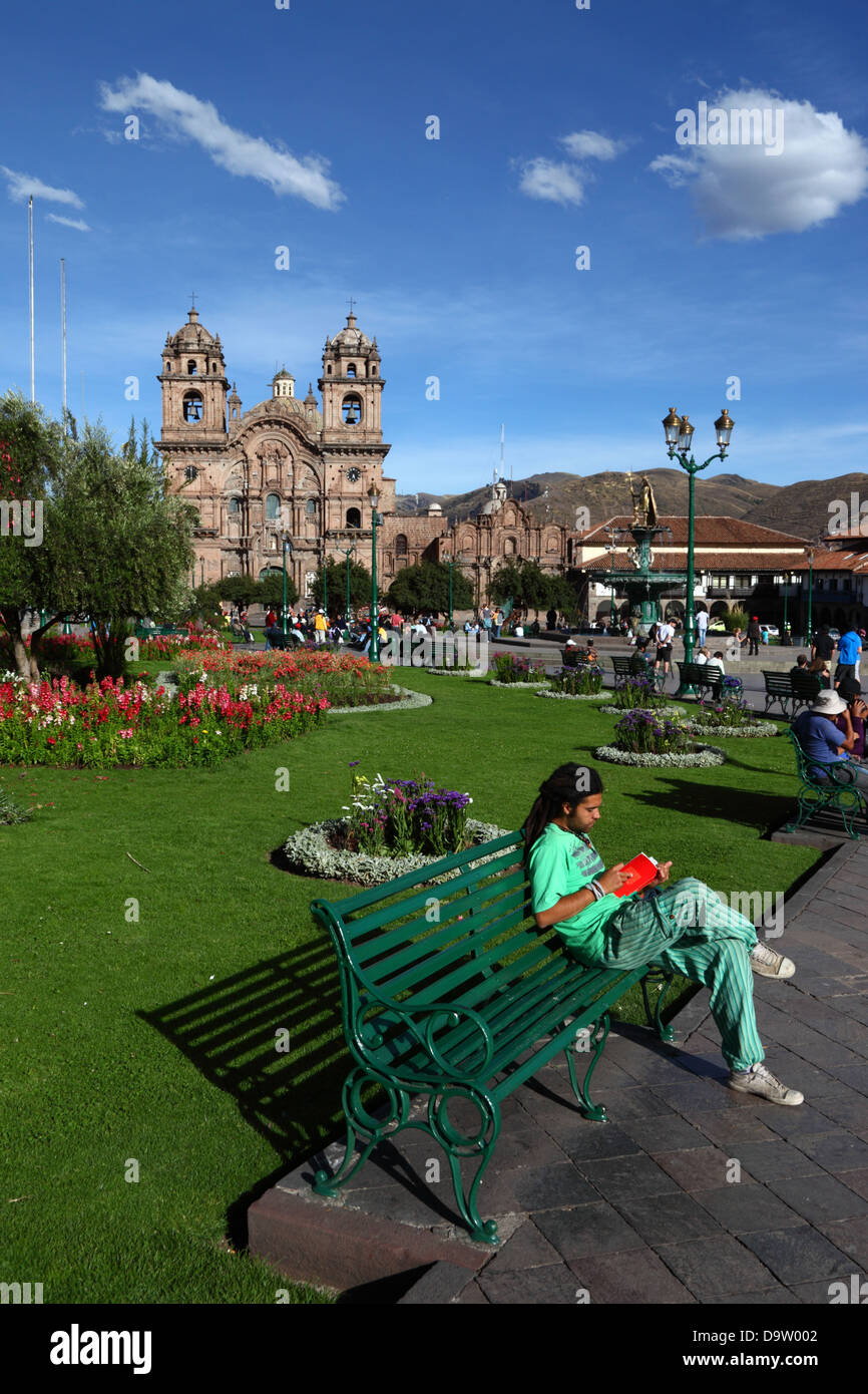 Backpacker leggendo un libro , Compañia de Jesus chiesa in sfondo , Plaza de Armas , Cusco, Perù Foto Stock