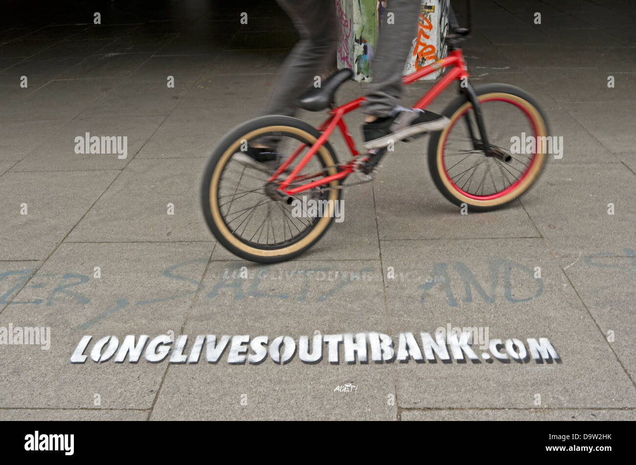 Un rider BMX cicli passato una pubblicità stencil l'url del sito web longlivesouthbank.com. Foto Stock