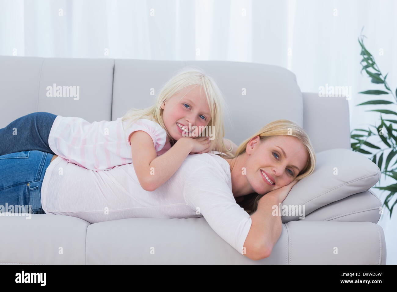 Madre sdraiato sul lettino con sua figlia sulla sua schiena Foto Stock