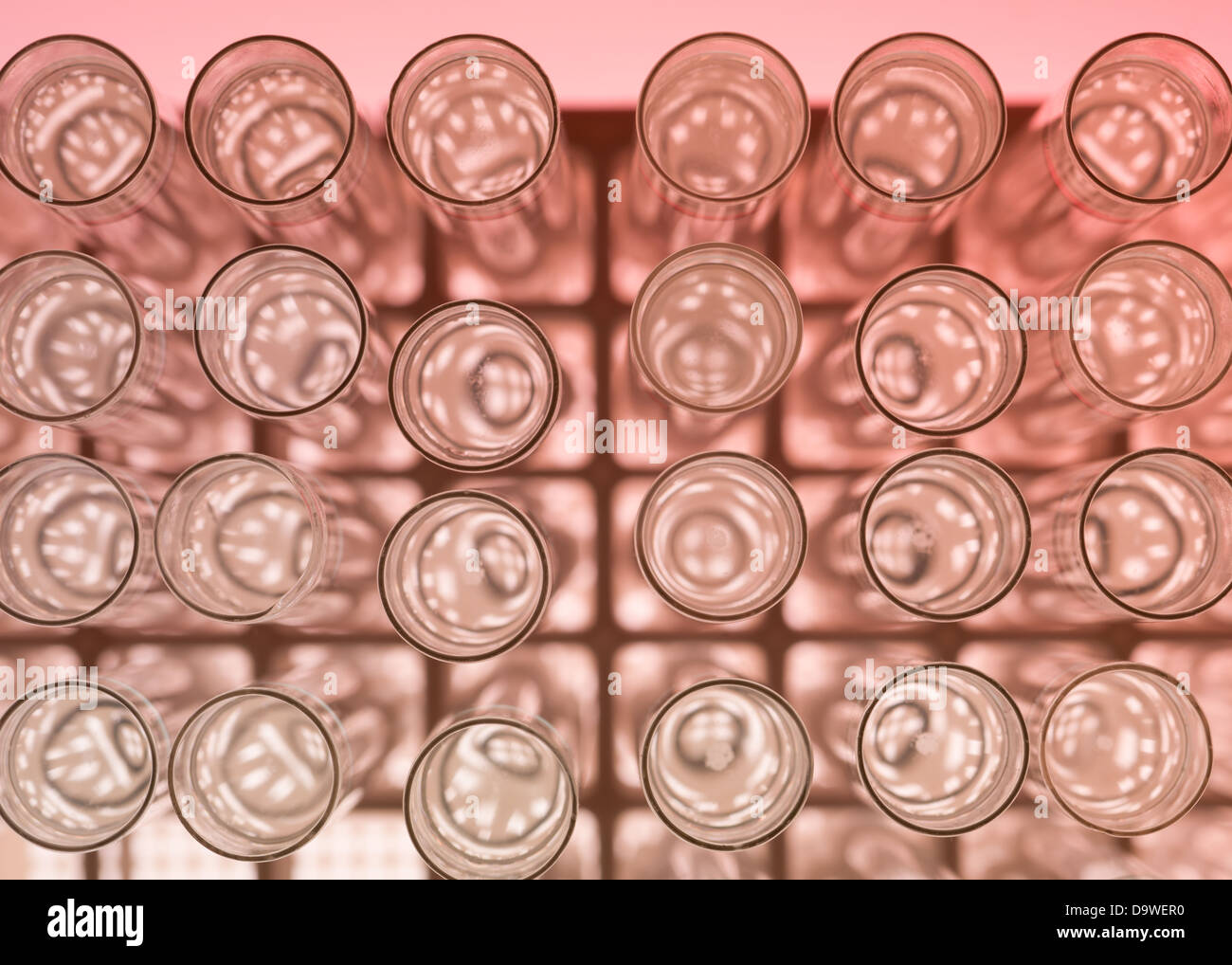 Vista superiore, macro di un banco di prova di laboratorio con provette in vetro riempito con liquido su uno sfondo rosso Foto Stock