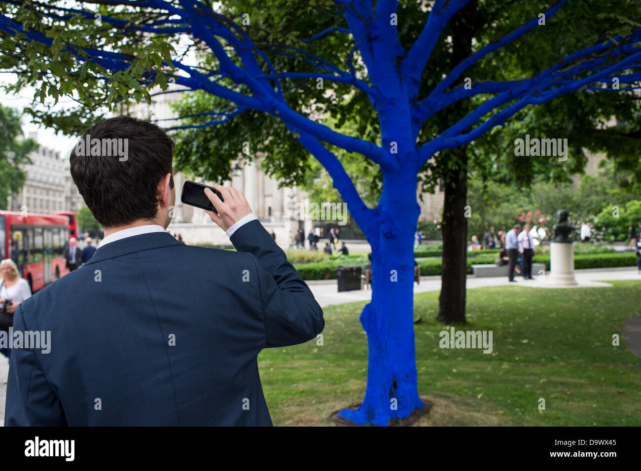 Londra, Regno Unito. Il 27 giugno 2013. Festival dei giardini, città di Londra. Le persone interagiscono con uno degli alberi dipinto di blu come parte di blu e di alberi in London arte di installazione. Alberi di carità per le città ha collaborato con artisti internazionali, Konstantin Dimopoulos, che è venuto fino al Blue Tree concetto. L idea del progetto è di convincere la gente a smettere di avviso e gli alberi nell'ambiente urbano. Come città popolazioni crescano, il numero di alberi di urbano diminuisce. Ma molte persone arrestato oggi a guardare, toccare e fotografare uno degli alberi di blu. Credito: Allsorts Stock Photo/Alamy Live News Foto Stock