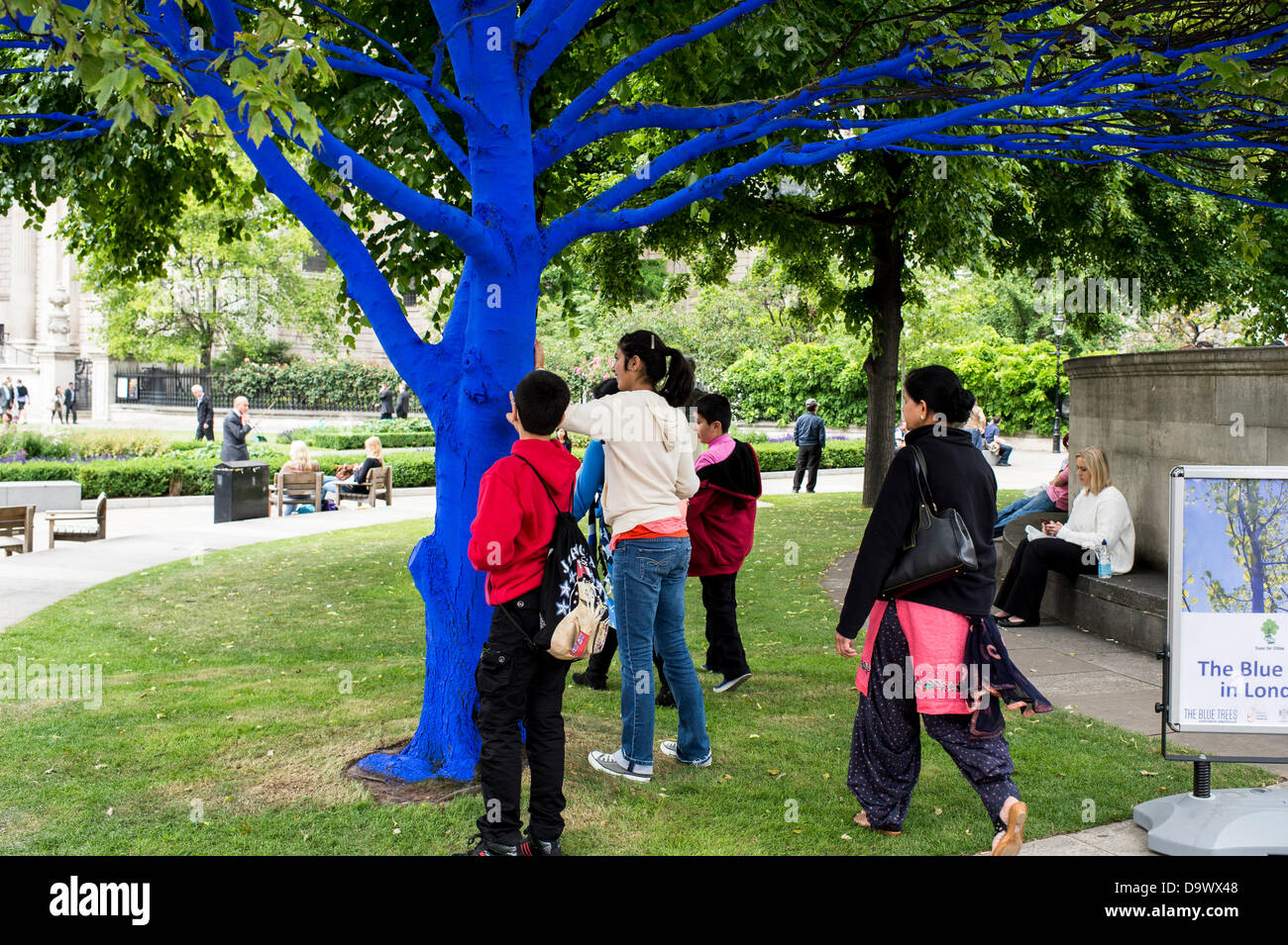 Londra, Regno Unito. Il 27 giugno 2013. Festival dei giardini, città di Londra. Le persone interagiscono con uno degli alberi dipinto di blu come parte di blu e di alberi in London arte di installazione. Alberi di carità per le città ha collaborato con artisti internazionali, Konstantin Dimopoulos, che è venuto fino al Blue Tree concetto. L idea del progetto è di convincere la gente a smettere di avviso e gli alberi nell'ambiente urbano. Come città popolazioni crescano, il numero di alberi di urbano diminuisce. Ma molte persone arrestato oggi a guardare, toccare e fotografare uno degli alberi di blu. Credito: Allsorts Stock Photo/Alamy Live News Foto Stock