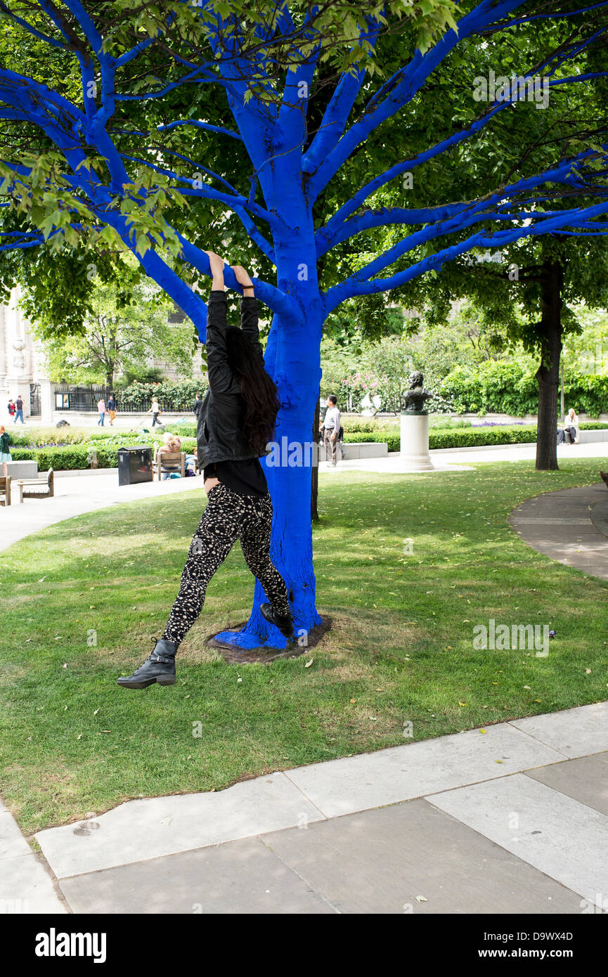 Londra, Regno Unito. Il 27 giugno 2013. Festival dei giardini, città di Londra. Le persone interagiscono con uno degli alberi dipinto di blu come parte di blu e di alberi in London arte di installazione. Alberi di carità per le città ha collaborato con artisti internazionali, Konstantin Dimopoulos, che è venuto fino al Blue Tree concetto. L idea del progetto è di convincere la gente a smettere di avviso e gli alberi nell'ambiente urbano. Come città popolazioni crescano, il numero di alberi di urbano diminuisce. Ma molte persone arrestato oggi a guardare, toccare e fotografare uno degli alberi di blu. Credito: Allsorts Stock Photo/Alamy Live News Foto Stock