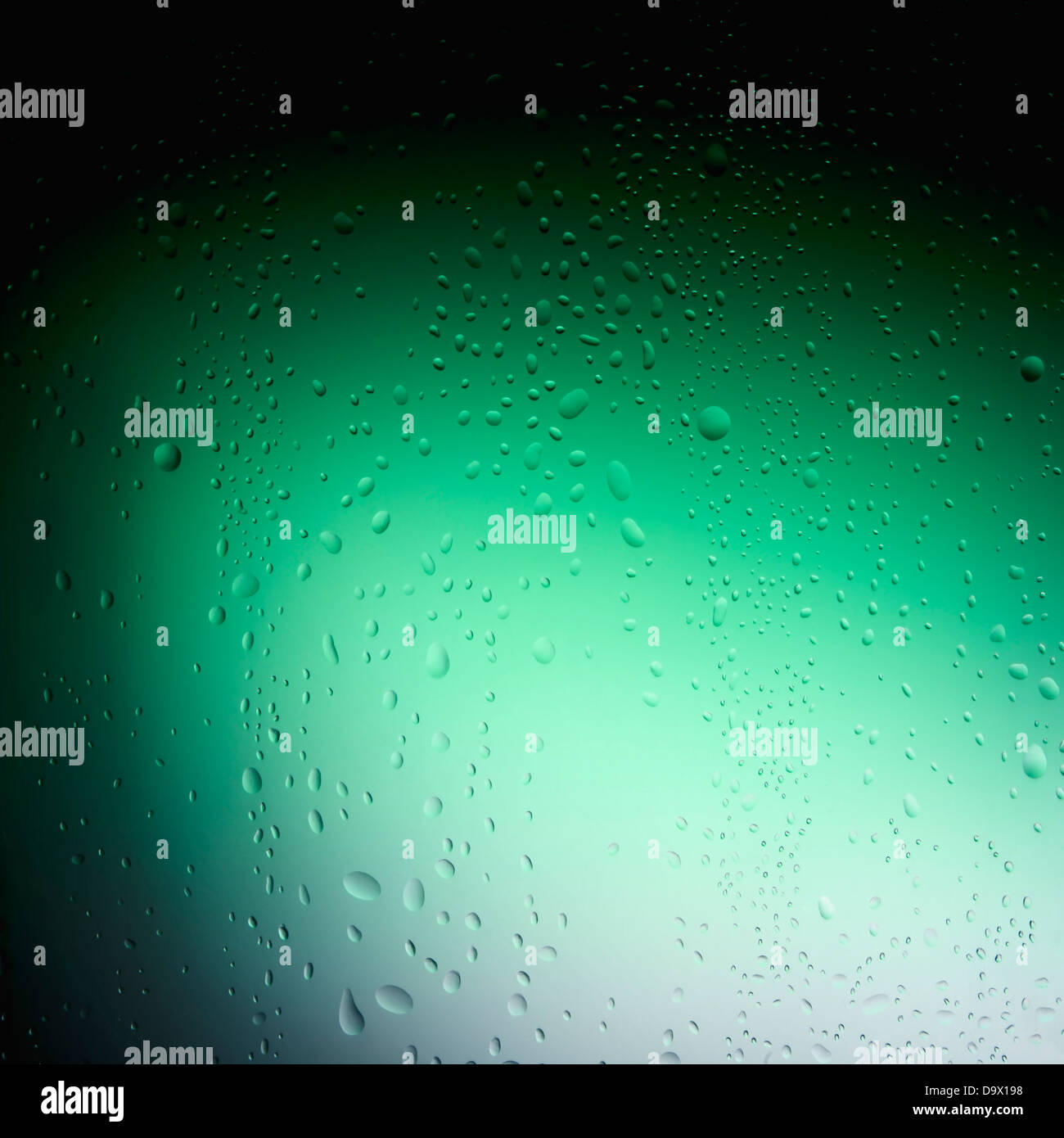Gocce d'acqua sul vetro dietro uno sfondo verde Foto Stock