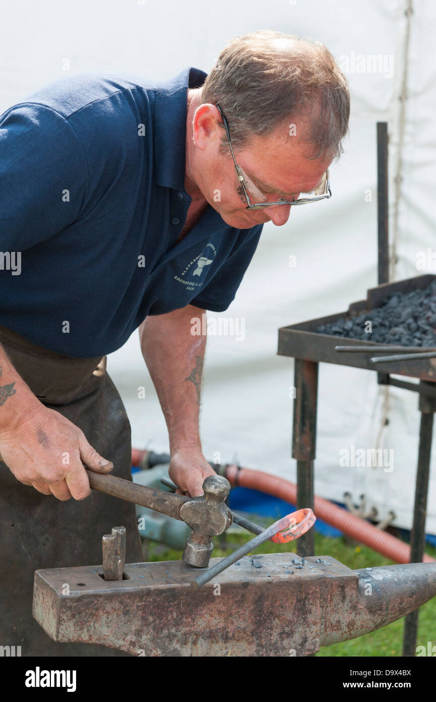 Un fabbro di martellatura a caldo rosso metallico su una incudine durante un concorso presso il Royal Cornwall Show 2013 Foto Stock