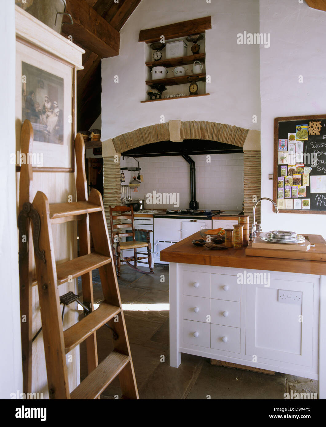 Scaletta in legno appoggiata contro la parete di soffitto alto del paese  bianco cucina con isola bianca unità e Aga forno Foto stock - Alamy