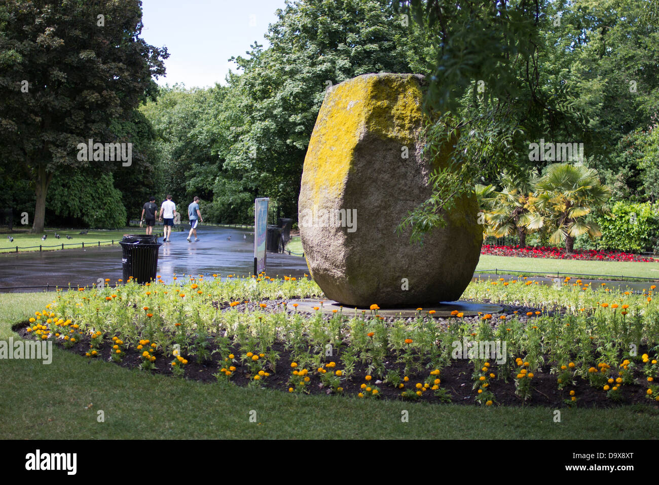 Una grande pietra eretta costituisce il punto centrale di un letto circolare colorato in un parco paesaggistico a Dublino, Irlanda, nel 2013. Foto Stock
