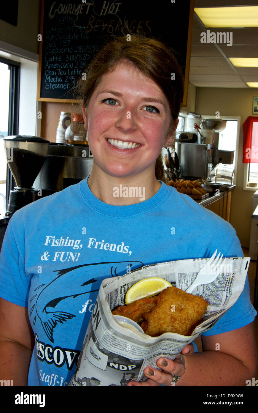 Giovane donna sorridente server ordine enorme pesce e patatine cono di giornale scoperta Molo Pesca concessione alimentare stand Foto Stock