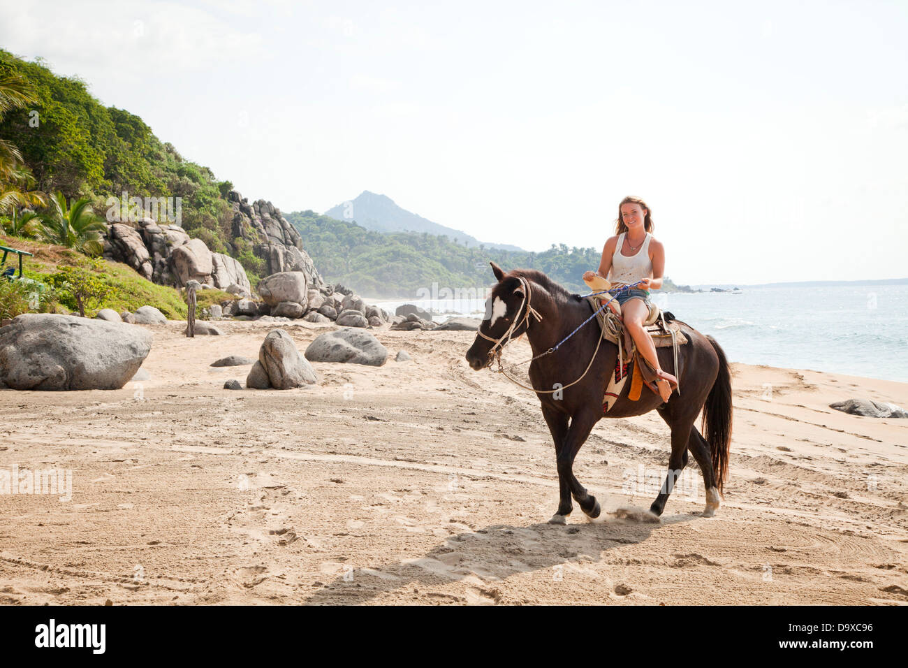 Giovane donna a cavallo sulla spiaggia Foto Stock