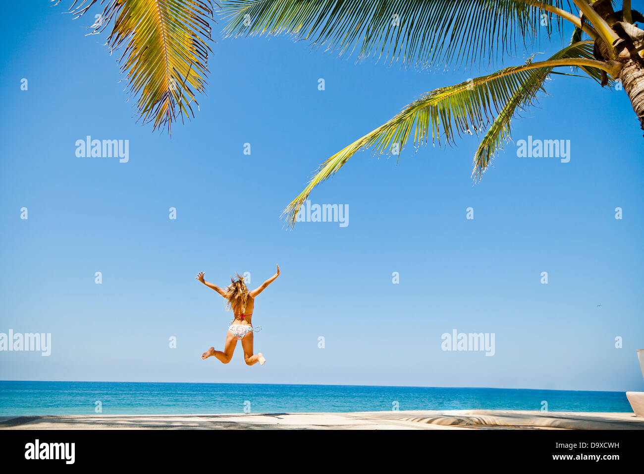 Donna in bikini salto sulla spiaggia Foto Stock