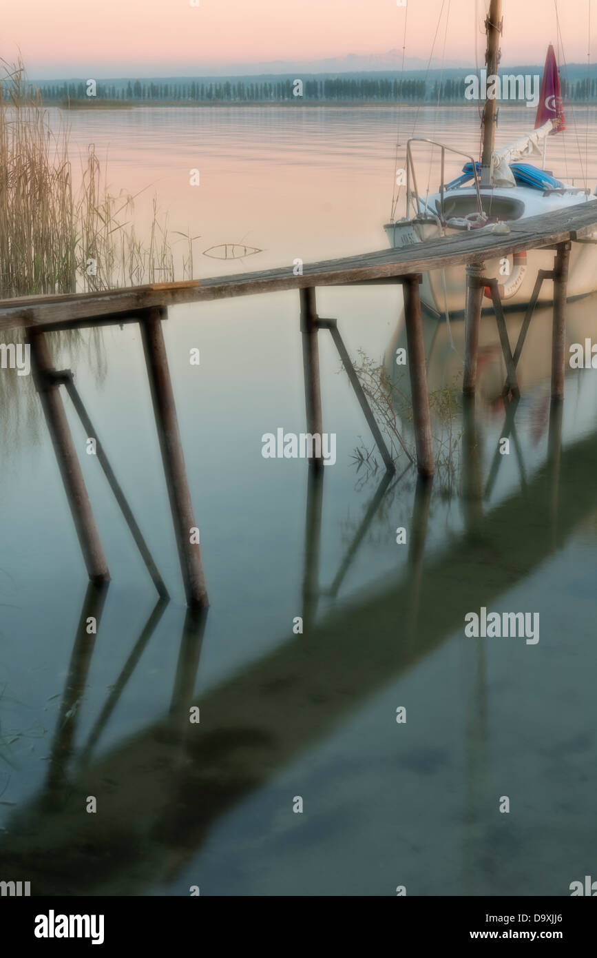 Germania, barca accanto al molo riflettendo in acqua al Lago di Costanza Foto Stock