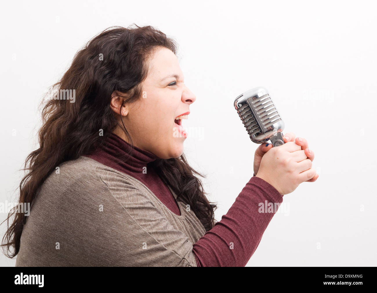 Donna urlare e afferra un microfono isolati su sfondo bianco. Foto Stock