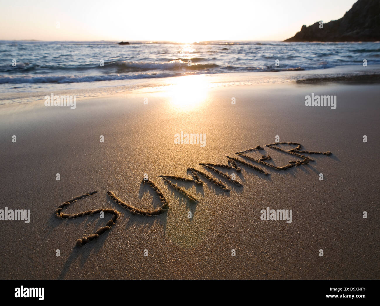 Estate di parola scritta nella sabbia di una spiaggia in una bella giornata di sole del tramonto. Foto Stock